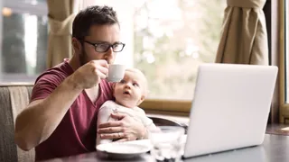 Ouder met koffie en baby aan het werk